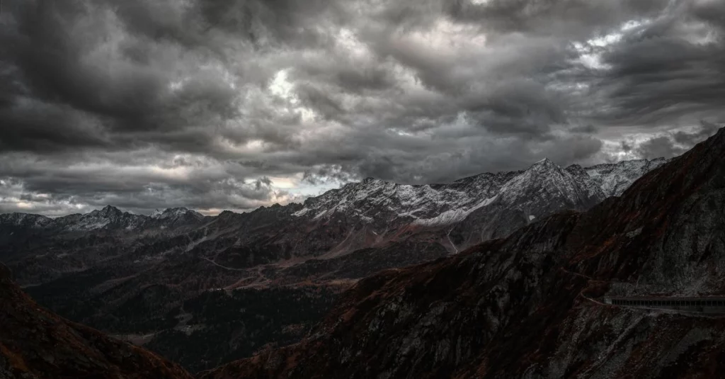 Symbolbild: Dunkle Sturmwolken über einer Schweizer Alpenlandschaft mit schneebedeckten Gipfeln.