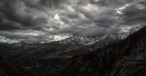 Symbolbild: Dunkle Sturmwolken über einer Schweizer Alpenlandschaft mit schneebedeckten Gipfeln.