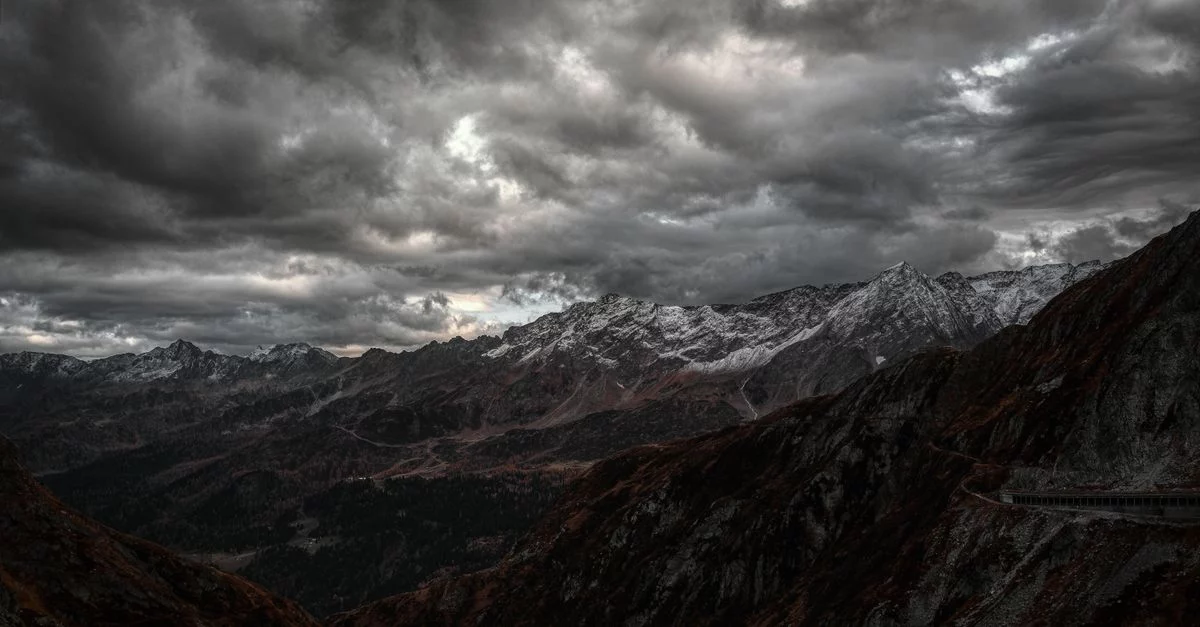 Symbolbild: Dunkle Sturmwolken über einer Schweizer Alpenlandschaft mit schneebedeckten Gipfeln.