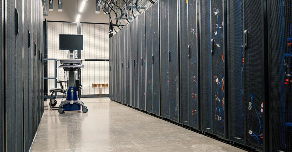 Symbolbild: Reihe hoher Serverschränke mit sichtbaren Kabeln und Netzwerkgeräten in einem Rechenzentrum.